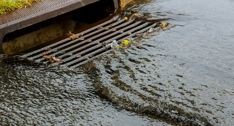 Water gushing from storm sewer following very heavy rainfall of the road after heavy rain.