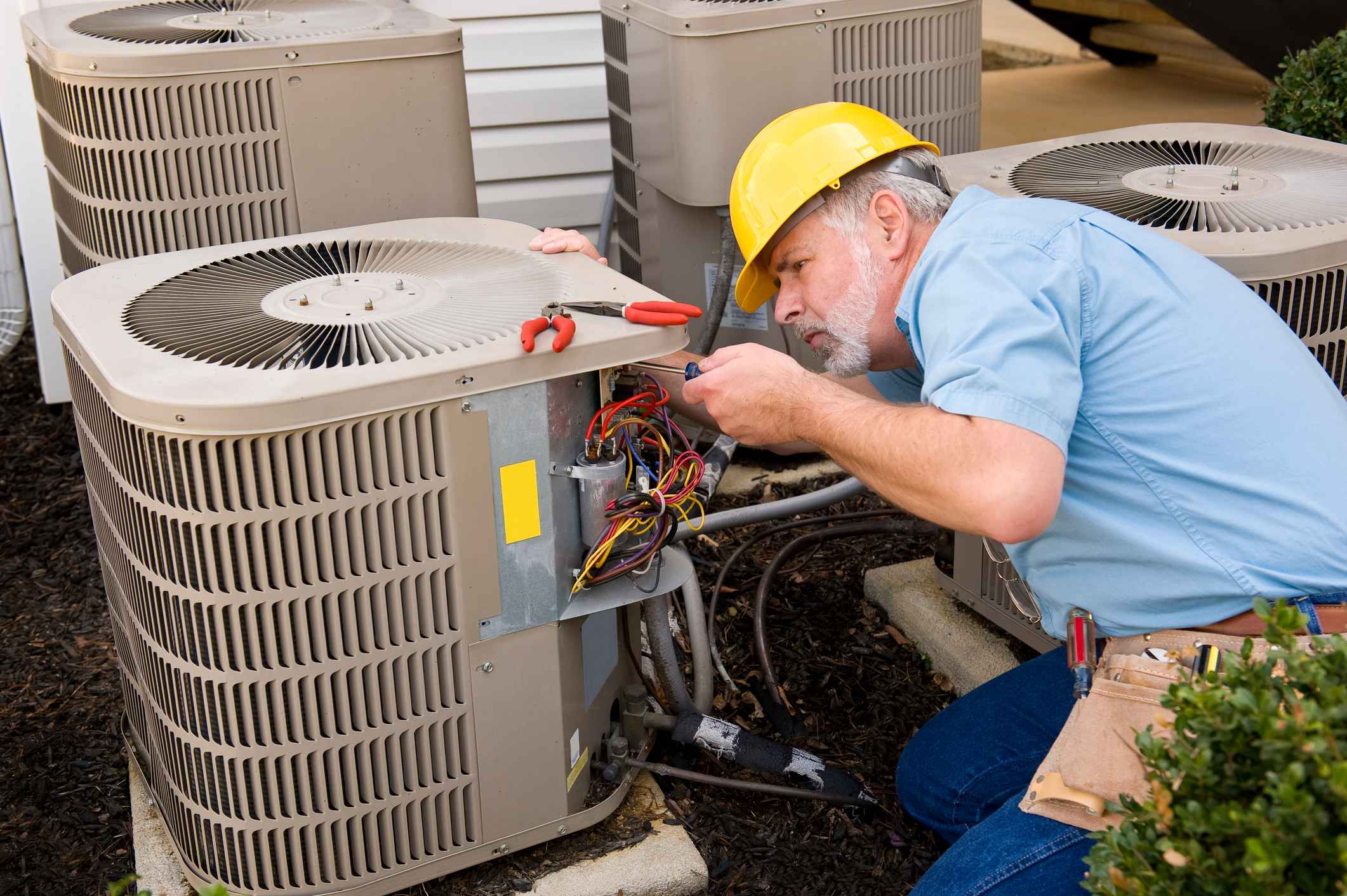 HVAC technician working on AC unit after replacement