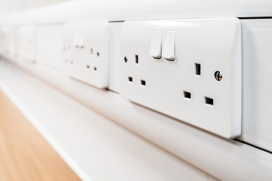 Shallow focus of newly fitted switchable 240 volt electrical sockets seen on a desk in a new office