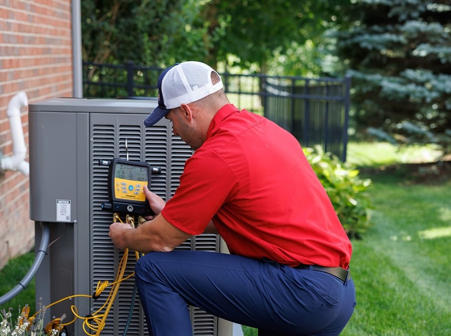 HVAC tech kneeling by air conditioning unit