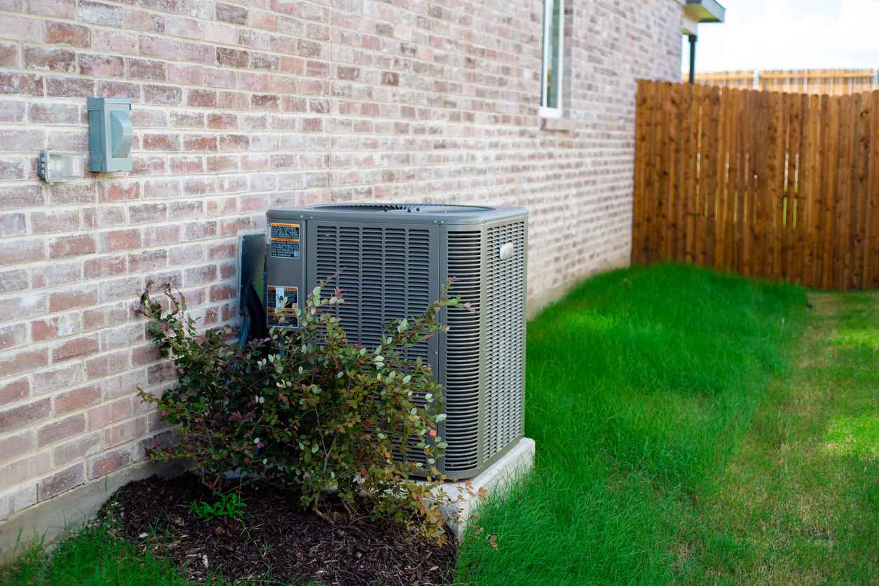 Outdoor air conditioner in the spring with bush surrounding it.